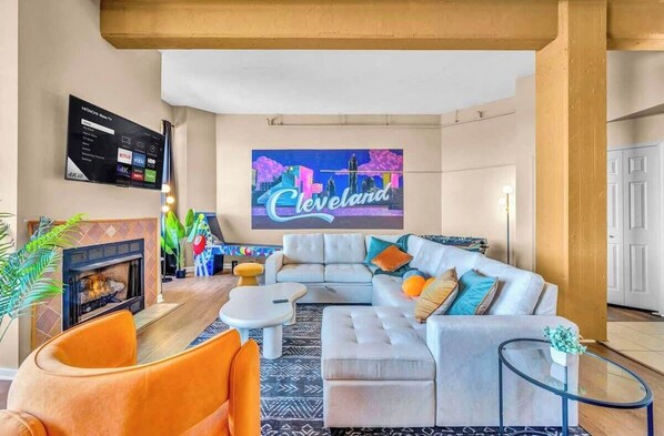 A modern living room with a large TV, a fireplace, and a cityscape mural.