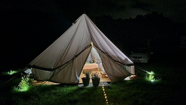 A tent set up in a grassy area at night with a vehicle parked nearby. - A Canopy under the Stars (Huntington)