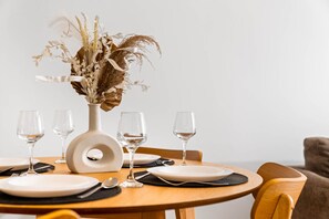 A dining table set with white plates, cutlery, and wine glasses, centered with a decorative vase of dried flowers. - Stylish Apartment * Balcony * Fast WiFi * Netflix (Birmingham)