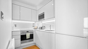 Eine moderne Küche mit weißen Schränken, einem Backofen, einer Spüle und einer Mikrowelle.