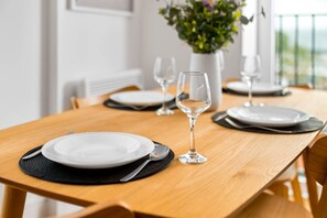 A dining table set with plates, cutlery, and wine glasses, with a potted plant in the background. - Luxury 2 Bedroom - Juliette Balcony - Fast Wi-Fi - Netflix (Birmingham)