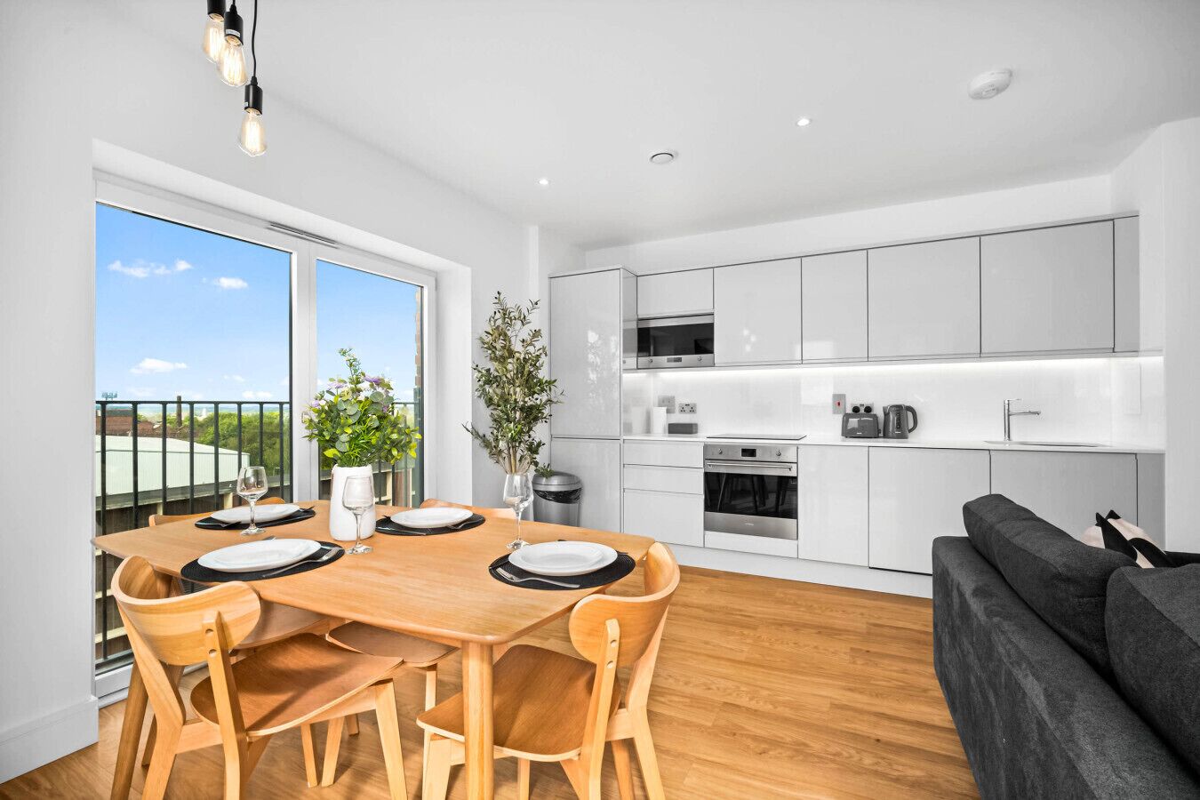 A modern kitchen with white cabinets, stainless steel appliances, and a dining area with a wooden table and chairs.
