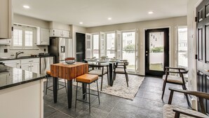 Een moderne keuken met een centraal eiland, barkrukken en een eethoek met stoelen.