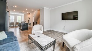 Una sala de estar moderna con un sofá, una mesa de centro y un televisor montado en la pared.