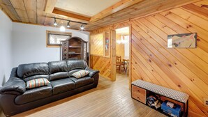 Un salon chaleureux avec un canapé en cuir, des murs en bois et une petite table sur laquelle sont posés un casque et une boîte.