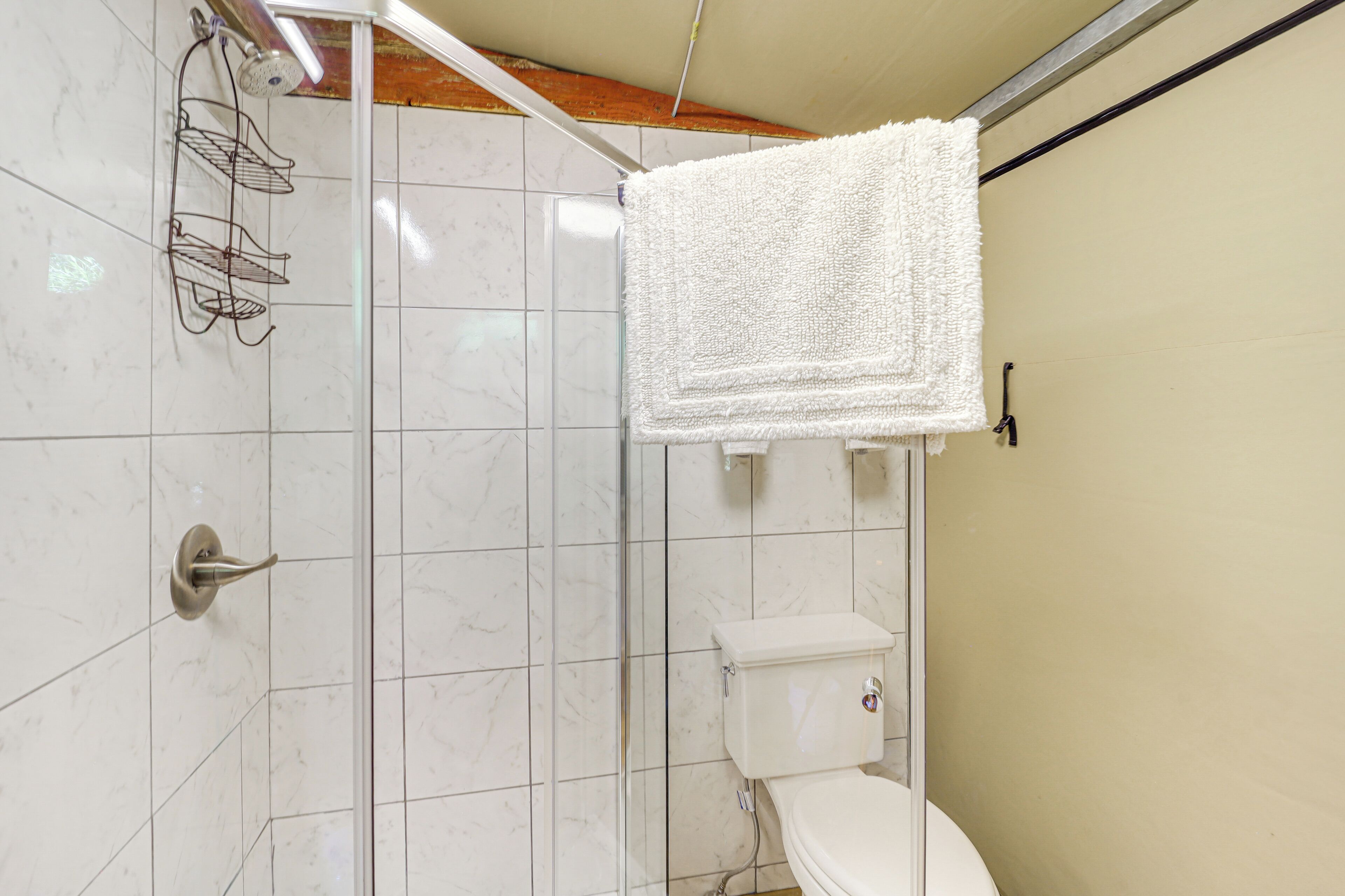 A bathroom with a shower, toilet, and towel hanging on the wall.