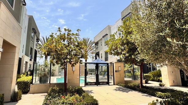 A modern building with a glass entrance, a pool, and well-maintained landscaping.
