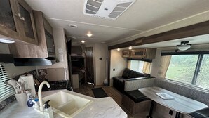 Une cuisine compacte pour camping-car, comprenant un évier, une cuisinière et des placards.