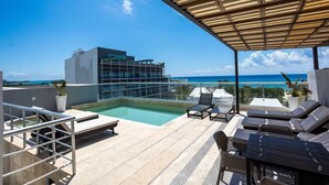 A rooftop pool area with lounge chairs and a view of the ocean. - Beautiful 2bd-2bth - Ocean Views (Playa del Carmen)