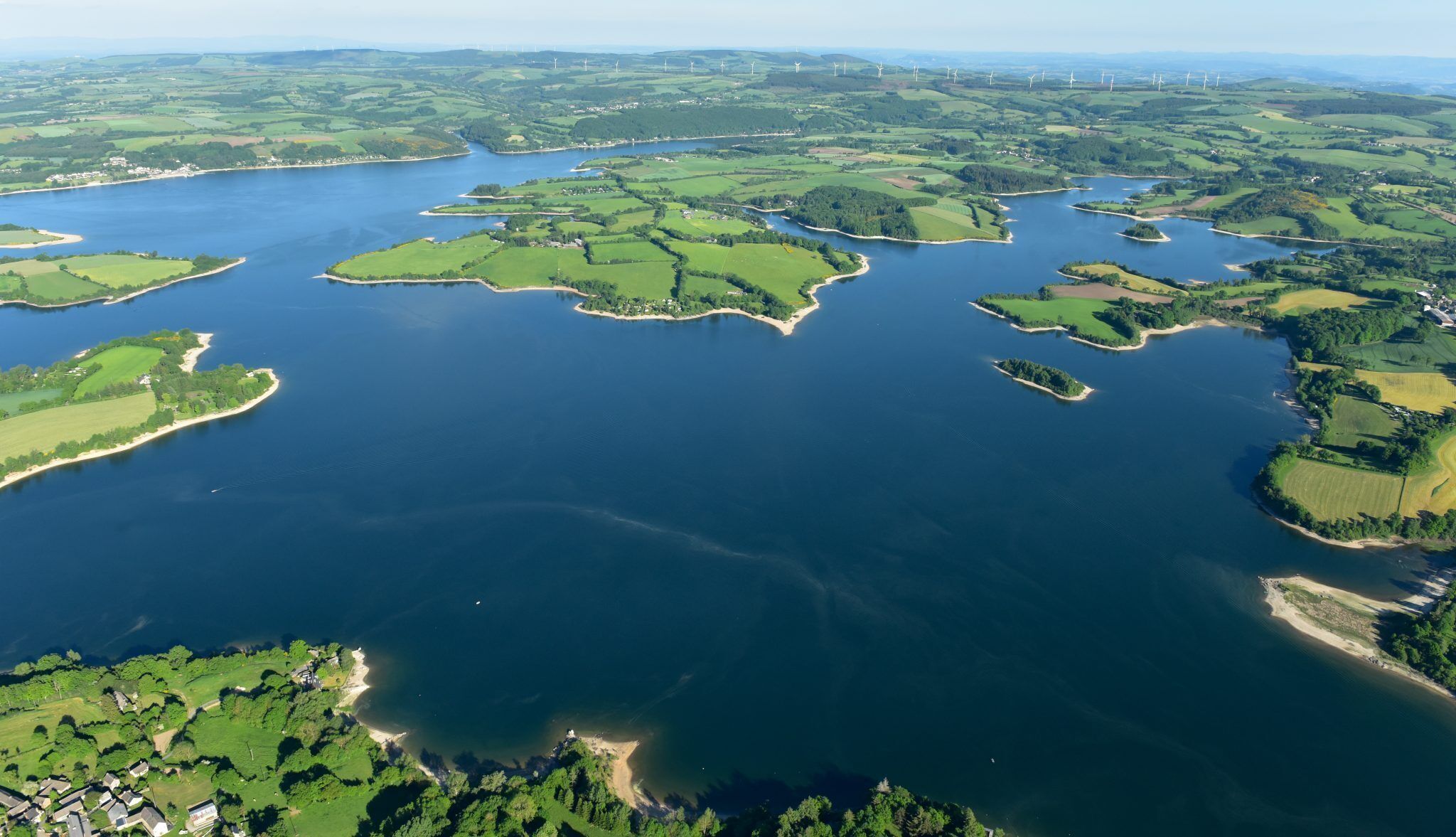 Une vue aérienne d’une zone côtière avec de nombreuses îles, une vaste étendue d’eau et des champs verdoyants environnants.