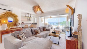 Una sala moderna con un amplio sofá modular, una mesita de centro y vista al océano.