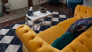 Un salon avec une cheminée, un téléviseur et deux fauteuils bleus.