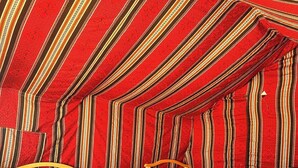 Een kamer met een schuine balklaag en een bed met een beddengoed met een patroon.