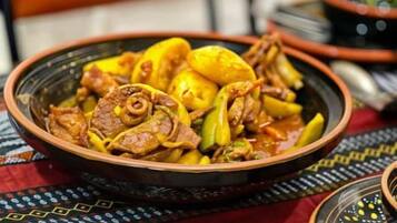 A traditional Moroccan dish, likely a tagine, served in a clay bowl on a patterned tablecloth.