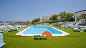 Une piscine avec des chaises longues, un ciel dégagé et une vue sur la mer.