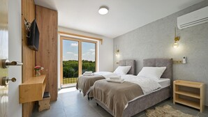 A modern bedroom with two beds, a wooden wardrobe, a TV, and a balcony with a view. - Beautiful home in Maglenca with sauna (Maglenca)