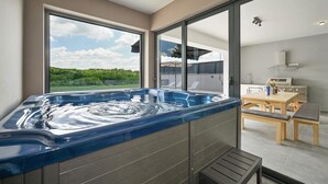 A modern bathroom with a large bathtub, a shower area, and a view of a lush garden. - Beautiful home in Maglenca with sauna (Maglenca)