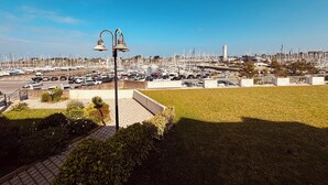 Un puerto deportivo con numerosos barcos, una zona de estacionamiento y un campo cubierto de césped.