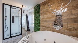 Un baño moderno con cabina de ducha de vidrio, una bañera grande y una pared de madera con un espejo decorativo.