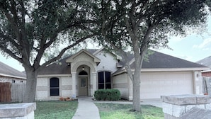 A residential house with a stone facade, a front entrance with an archway, a driveway, and a garage.