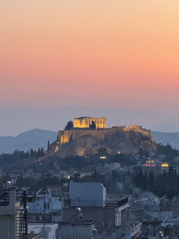 Vue de l’Acropole d’Athènes, avec le Parthénon illuminé sur fond de ciel au coucher du soleil.