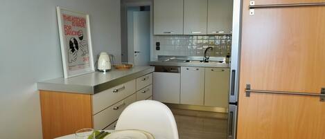 Una cocina moderna con armarios blancos, una mesa de comedor para dos personas y un cartel en la pared.