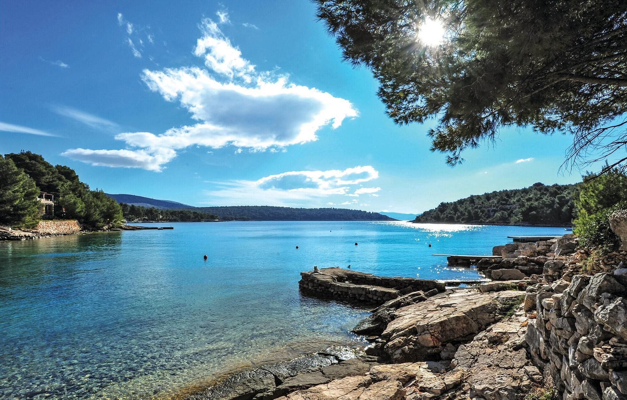 Vista deslumbrante de um lago tranquilo, rodeado por margens rochosas e árvores densas.