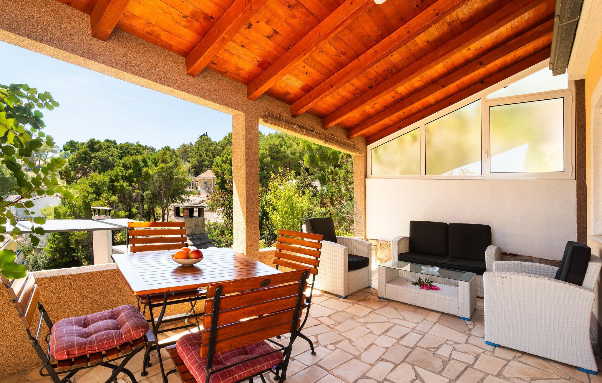 Un patio esterno con tavolo, sedie e divano in legno.