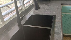 Una cocina con un lavamanos de acero inoxidable, un grifo y una ventana con vistas al exterior.