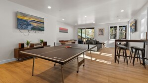 Un salon moderne avec une table de ping-pong, un canapé, une table basse et un téléviseur.