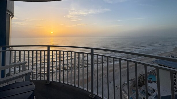 A balcony with a view of the ocean at sunset. - 24th Floor OceanView Oasis (Daytona Beach Shores)