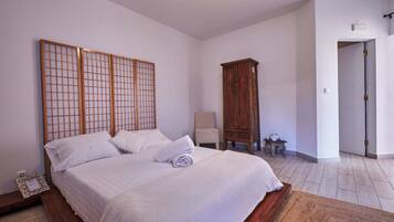 Une chambre avec un grand lit, une armoire en bois et une chaise.