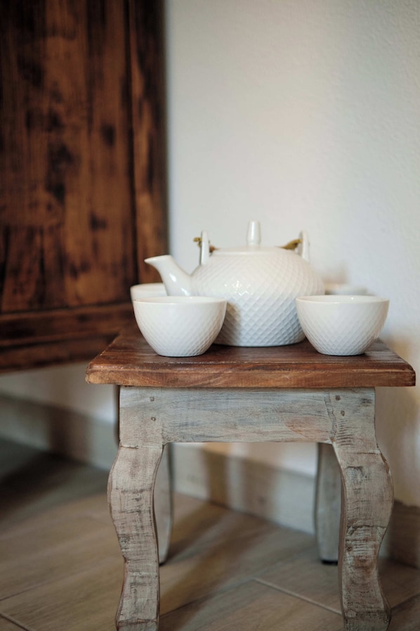 A rustic wooden table with white ceramic bowls and a teapot.