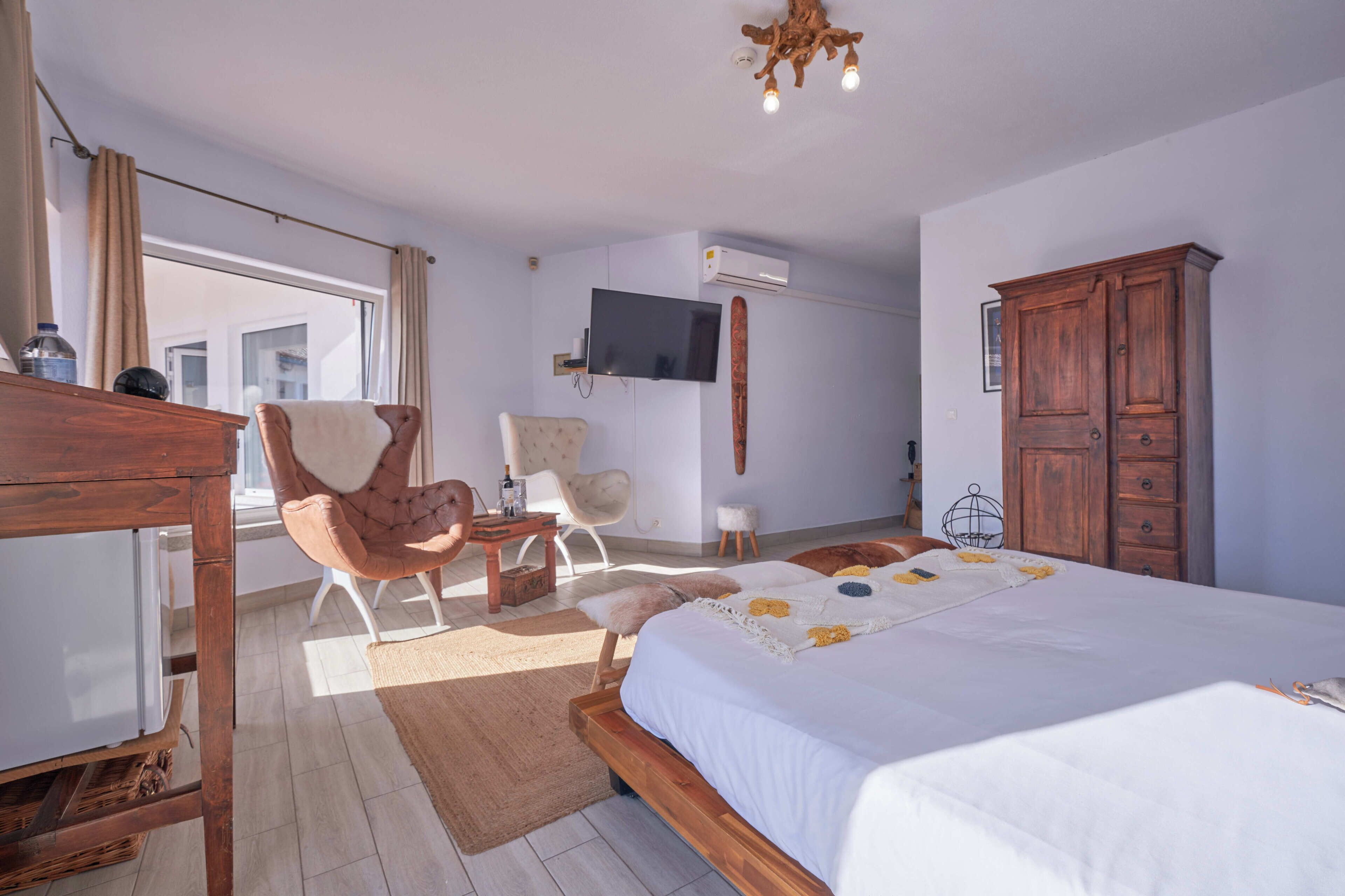 Ein Schlafzimmer mit einem großen Bett, Holzmöbeln, einem Fernseher und einem Fenster mit Vorhängen.