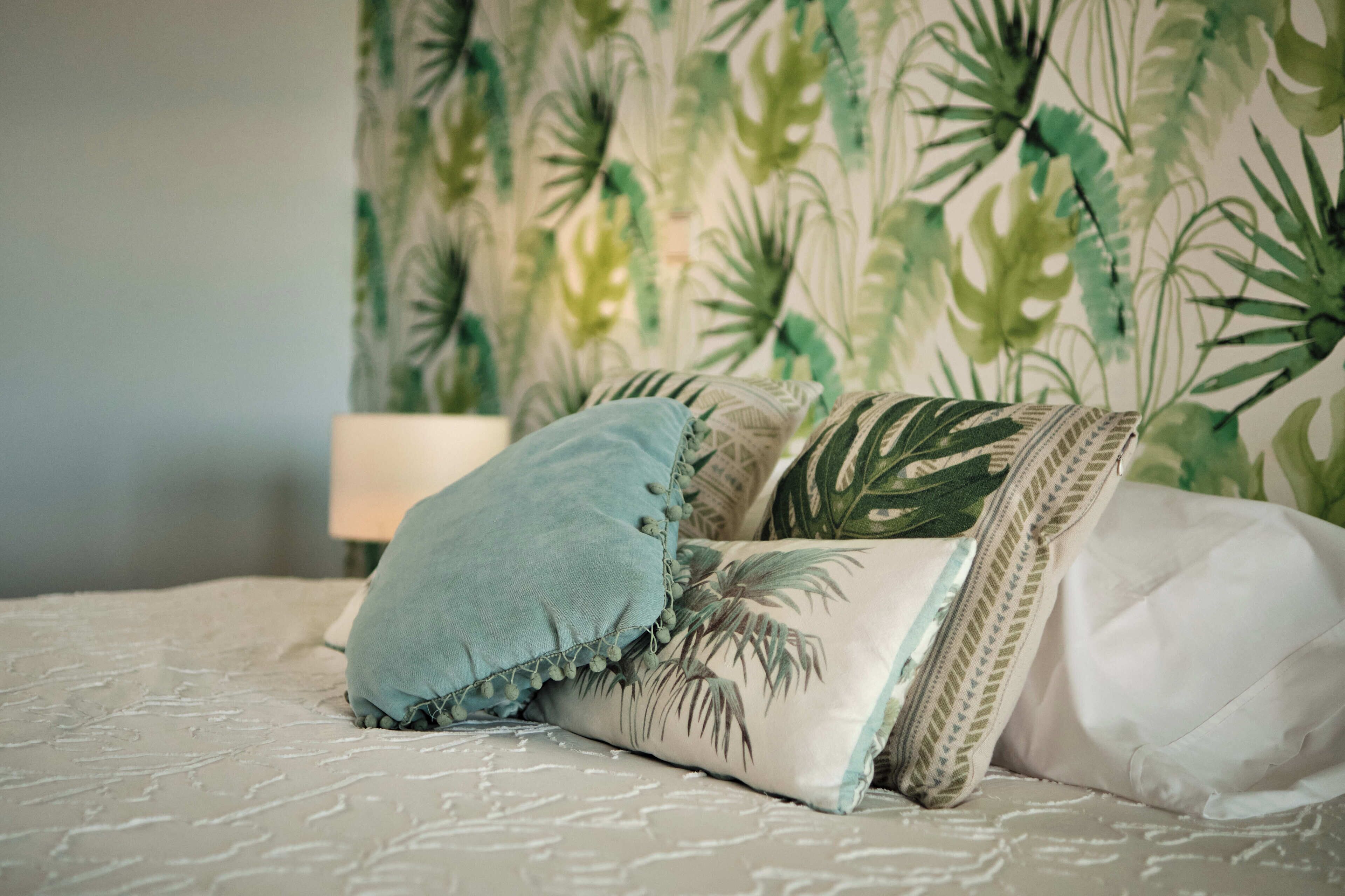 A bed with a patterned bedspread and decorative pillows.