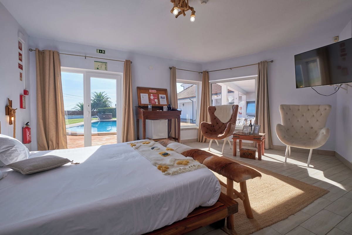 Une chambre d’hôtel avec un grand lit, un bureau, une chaise, une télévision et une vue sur une piscine.