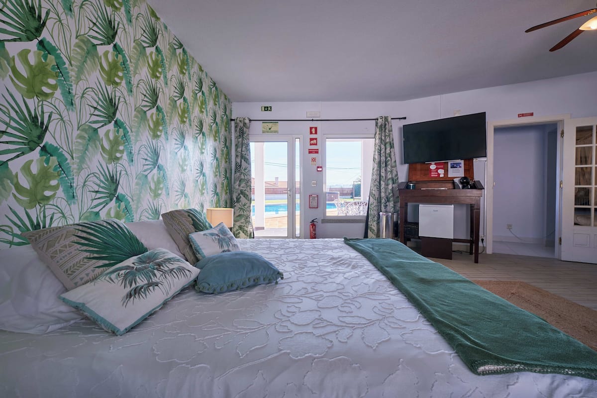 Une chambre d’hôtel équipée d’un lit, d’un bureau, d’une télévision et offrant une vue sur l’extérieur.