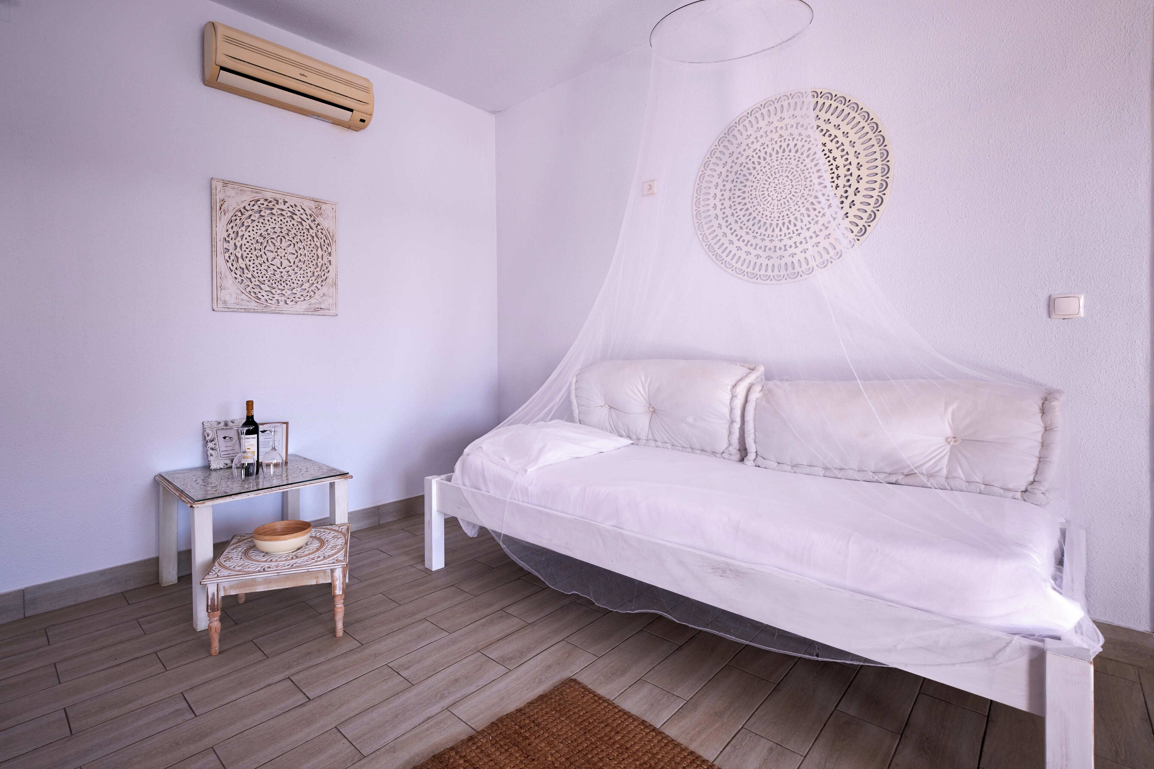 Une chambre à coucher avec un lit sous un dais, une table de chevet avec une bouteille et des verres, et un élément décoratif mural.