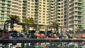 A high-rise hotel with a swimming pool, multiple balconies, and outdoor seating areas. - 2bd2bth Partial Ocean view Ste w/ balcony, Pool, nearby dining, beach access (Miami Beach)