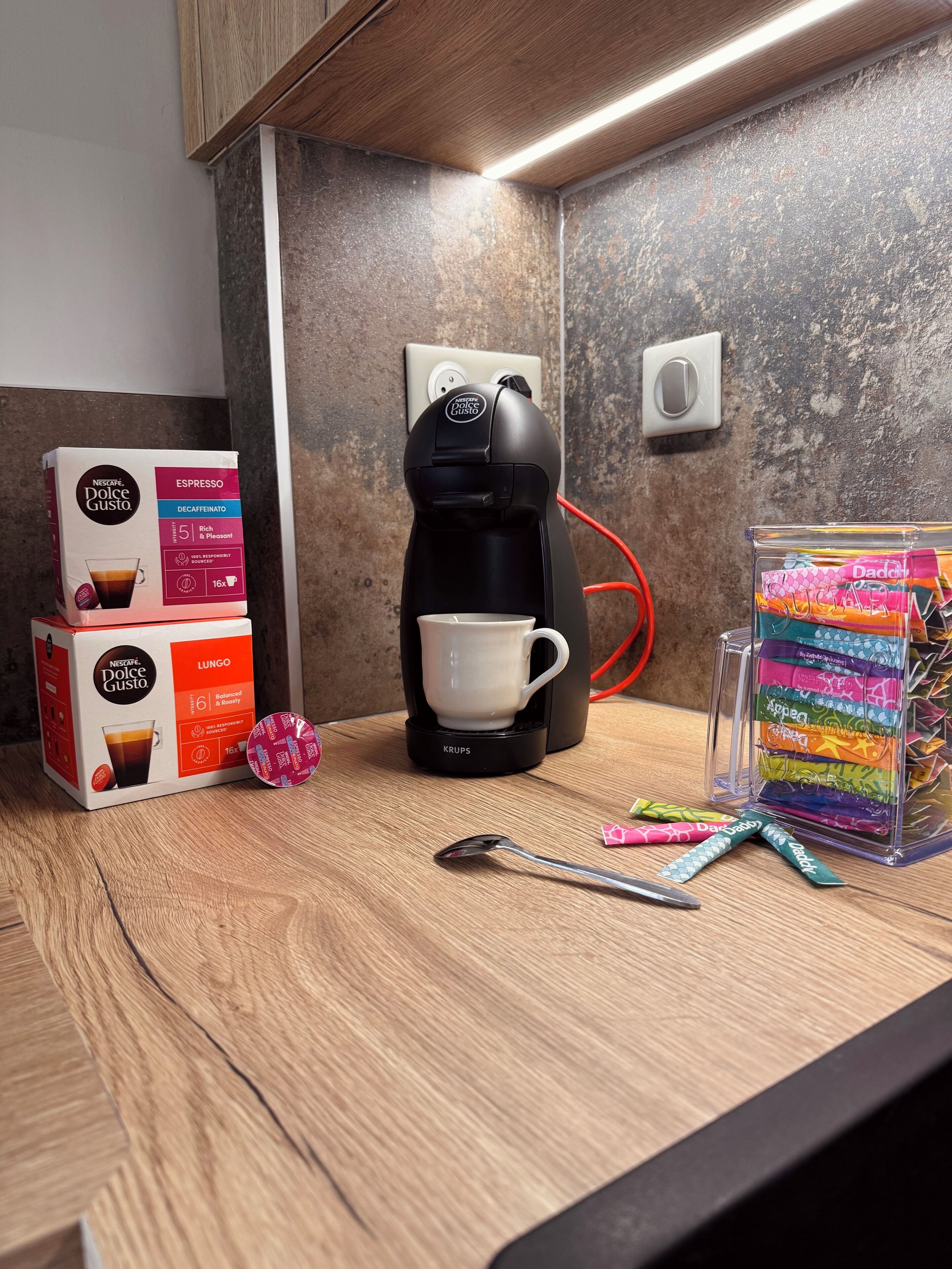 Een aanrecht met een koffiezetapparaat, een kop en koffiecups.