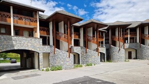 A building with a stone facade, wooden balconies, and a covered entrance. - Studio Hart 2 (Les Gets)