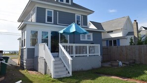 A two-story house with a covered porch and a wooden deck. - Island Time- 3BR Home | Water View Chincoteague Bay (Chincoteague)