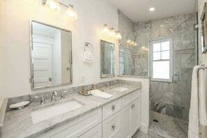 Un bagno con due lavandini, uno specchio grande e una zona doccia.