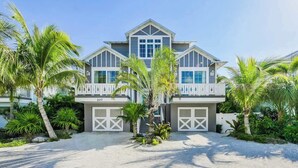 A two-story house with a balcony, garage doors, and a number '207' on the front. - Pineapple Paradise~WATER SLIDE/Heated Pool & Spa! (Holmes Beach)