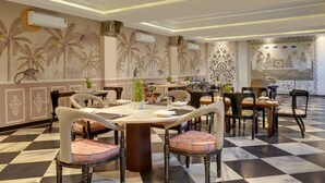 Un comedor con piso a cuadros, mesas con sillas y murales decorativos en las paredes.