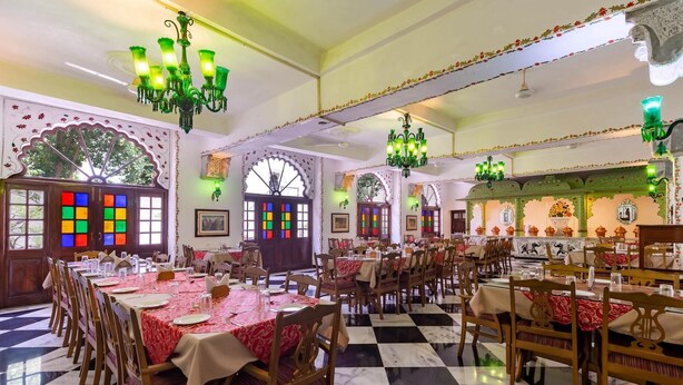 Un restaurante con varias mesas y sillas, candelabros ornamentales y paneles decorativos en las paredes.