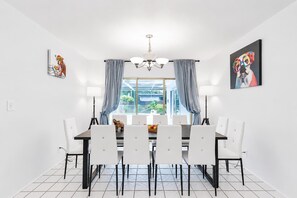 A dining area with a table, chairs, a chandelier, and artwork on the walls. - Villa Chill on the Hill (Hollywood)