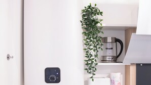 A modern kitchen with a built-in water heater, a coffee maker, a toaster, and a plant on the shelf.