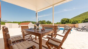 Un patio al aire libre con mesa y sillas de madera, una piscina y un muro de piedra.