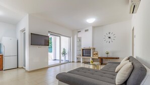 A modern living room with a grey sofa, a flat-screen TV, a clock, and a small table with a vase. - Two bedroom cozy apartment in Banjole (Banjole)